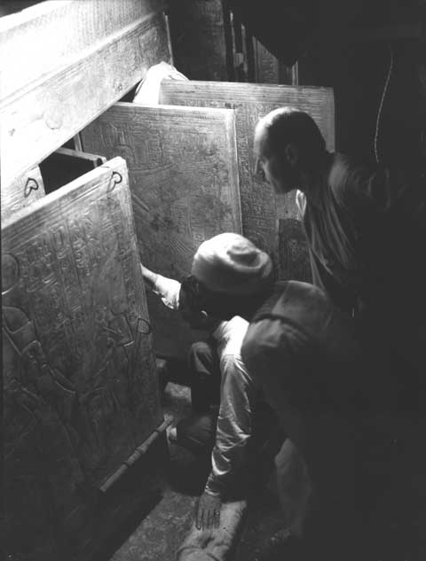 4th January 1923, Tutankhamun's Tomb. Howard Carter (kneeling), Arthur Callender, and an Egyptian workman in the Burial Chamber, looking through the open doors of the four gilded shrines towards the quartzite sarcophagus. Burton photograph 0643 © Griffith Institute, University of Oxford. 